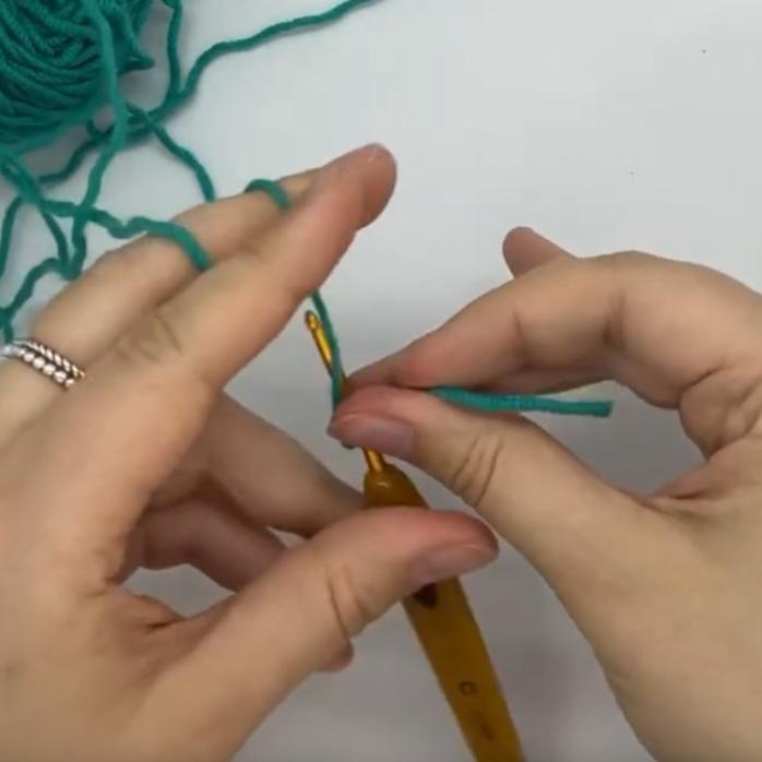 a screenshot from the linked video showing someone crocheting with only their left hand