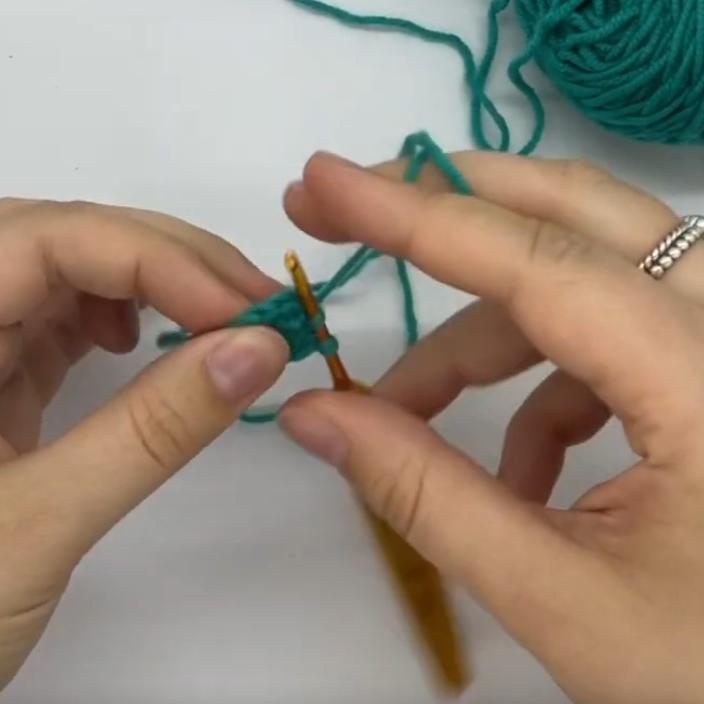 a screenshot from the linked video showing someone crocheting with only their right hand